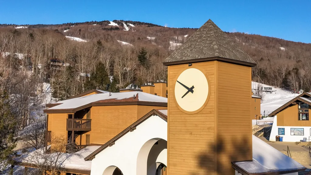 The clock tower at Okemo’s Clock Tower base area in Ludlow, Vermont, with ski trails behind it