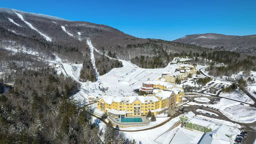 Aerial view of Okemo’s Jackson Gore base area in winter, with the Jackson Gore Village Inn, pool, lifts and parking lots